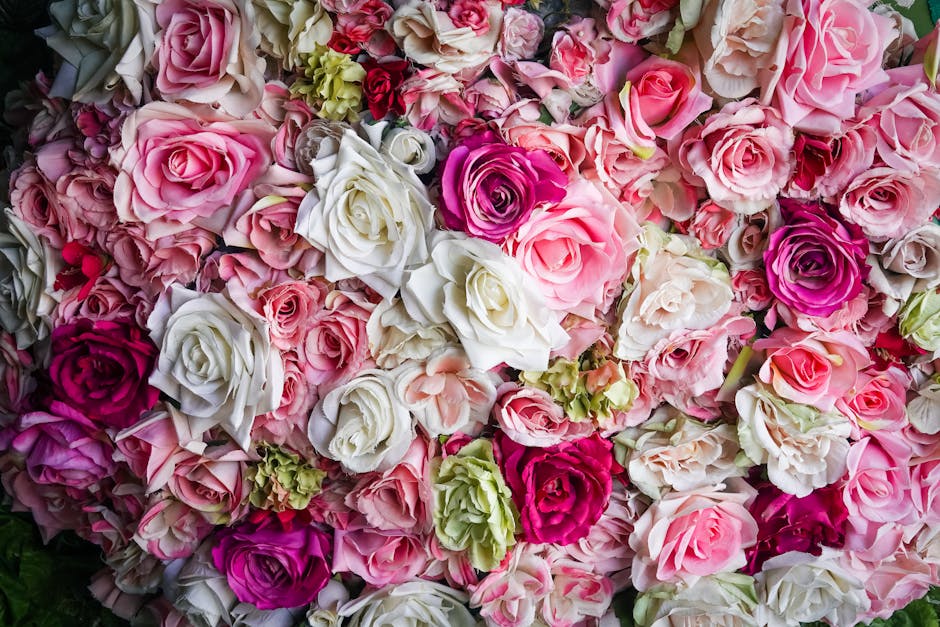 A dense arrangement of fresh roses in various shades of pink, white, and deep magenta, with some light green hydrangea blooms interspersed. The roses display layered petals with soft textures, with so